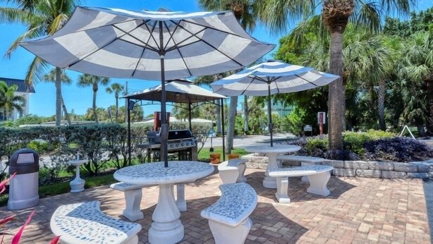 Terrasse mit Sonnenschirmen, Grill und angelegtem Garten mit Palmen.