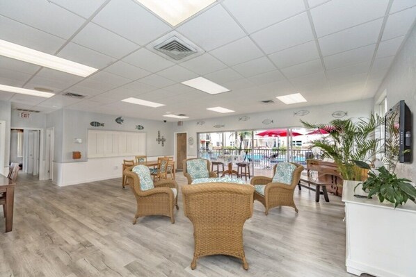 A spacious indoor area with wicker furniture, a pool view, and a white ceiling.