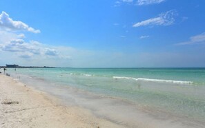 A beach with clear turquoise water, a sandy shore, and a distant city skyline. - Condo# 415 2 Bed/1 bath Condo Steps to Siesta Key Beach! (Sarasota)