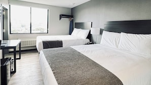 Habitación de hotel con dos camas, un escritorio, una silla y un ventanal.