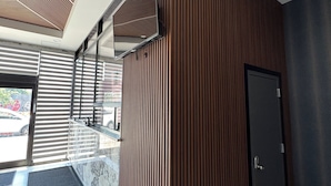 Un interior moderno con un panel de madera, una puerta negra y entrada de cristal.