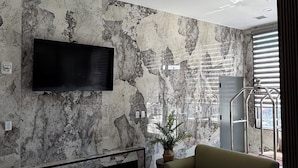 Un moderno hall de entrada con una gran televisi ón de pantalla plana montada en una pared texturizada, un sofá y una planta en maceta.