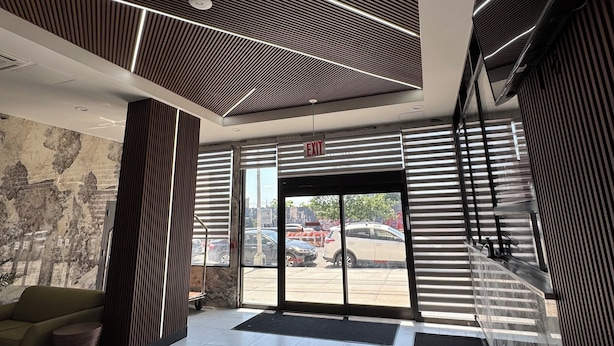 Un vestíbulo moderno con techo estampado, una recepción y vista al estacionamiento.