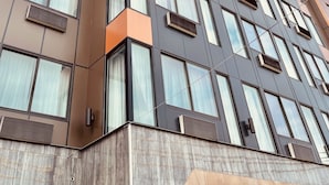 Un edificio de varios pisos con un diseño arquitectónico moderno, con grandes ventanales y una combinación de materiales de fachada en tonos marrón y gris.