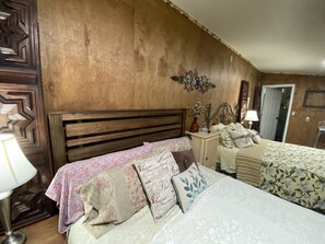 Cozy bedroom with a rustic aesthetic, featuring a wooden headboard, sloped ceiling, and floral-patterned bedding.