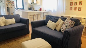 Ein Wohnzimmer mit zwei Sofas, einem Couchtisch und einer Küchenzeile im Hintergrund.
