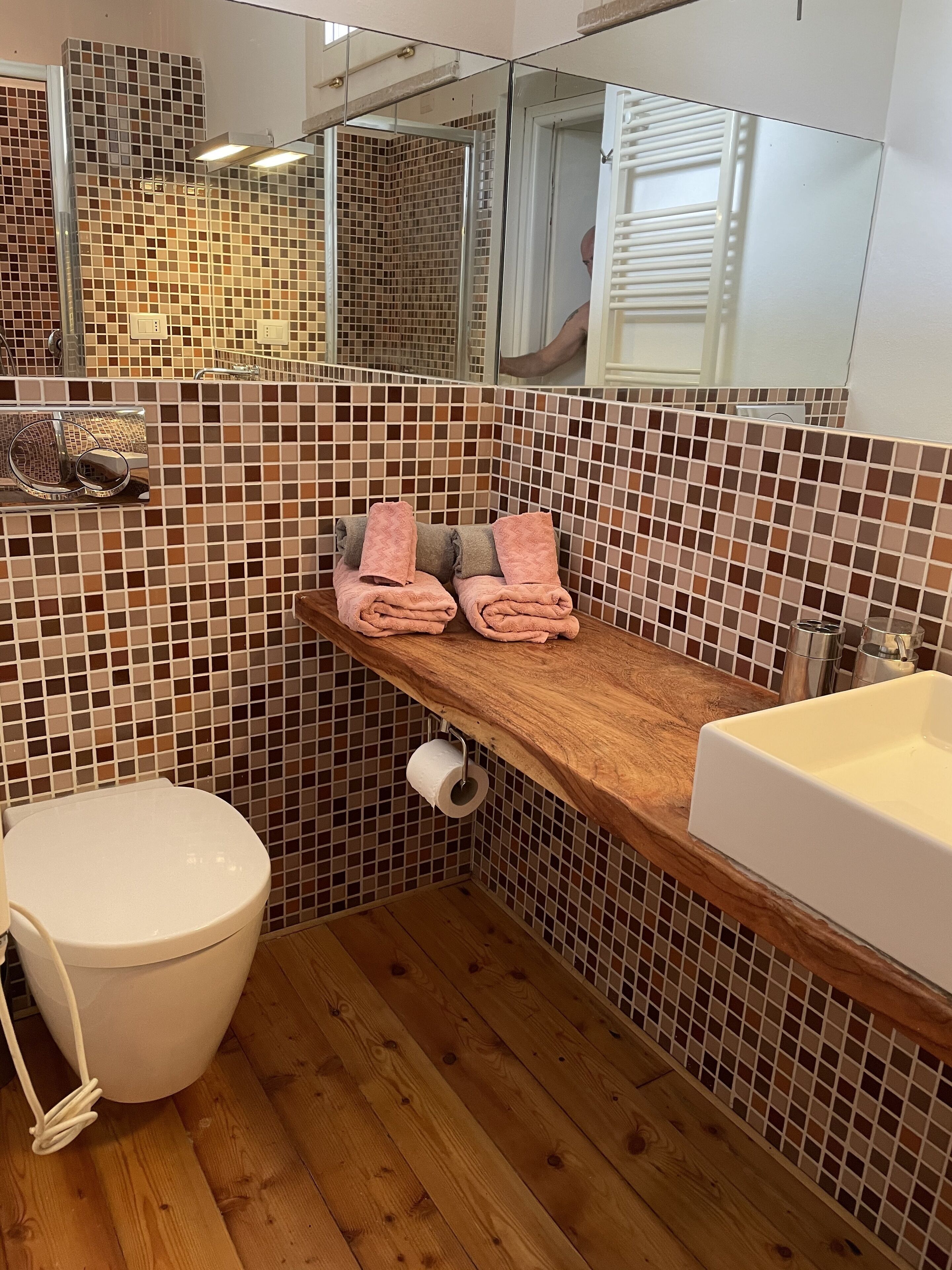 Un bagno con un mobile lavabo in legno, un lavandino bianco, un water e uno specchio.