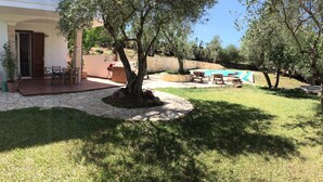 Eine Terrasse mit Gartenmöbeln, einem Swimmingpool und einem gepflasterten Weg.