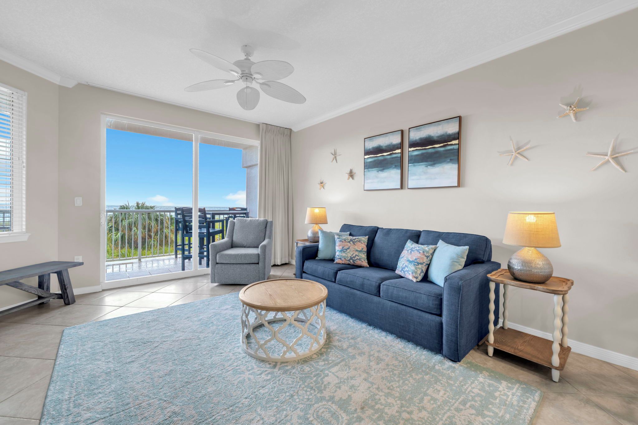 Ein Wohnzimmer mit einem blauen Sofa, einem runden Couchtisch und einem Balkon mit Aussicht.