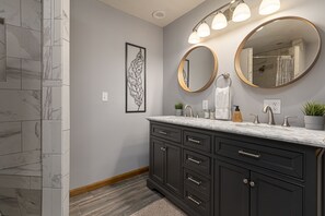 A bathroom with dark cabinets, a marble countertop, and two wall-mounted mirrors.