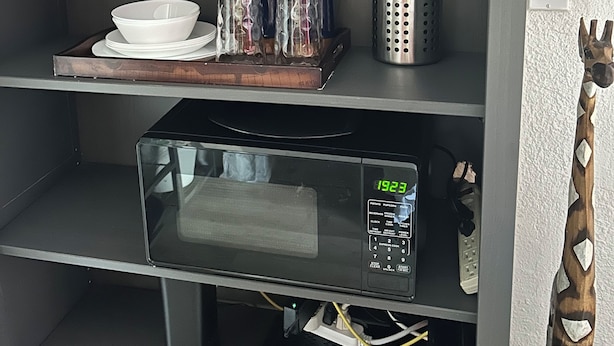 A kitchen shelf with a microwave, glassware, and a globe. - FANTASTIC LOCATION NEAR ALL ATTRACTIONS! (Orlando)