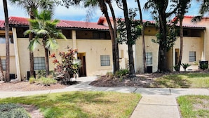 A building with a red-tiled roof, multiple windows, and a paved walkway leading to the entrance. - FANTASTIC LOCATION NEAR ALL ATTRACTIONS! (Orlando)