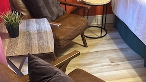 A cozy room with a brown leather chair, a small round table, and a bed with white bedding. - FANTASTIC LOCATION NEAR ALL ATTRACTIONS! (Orlando)