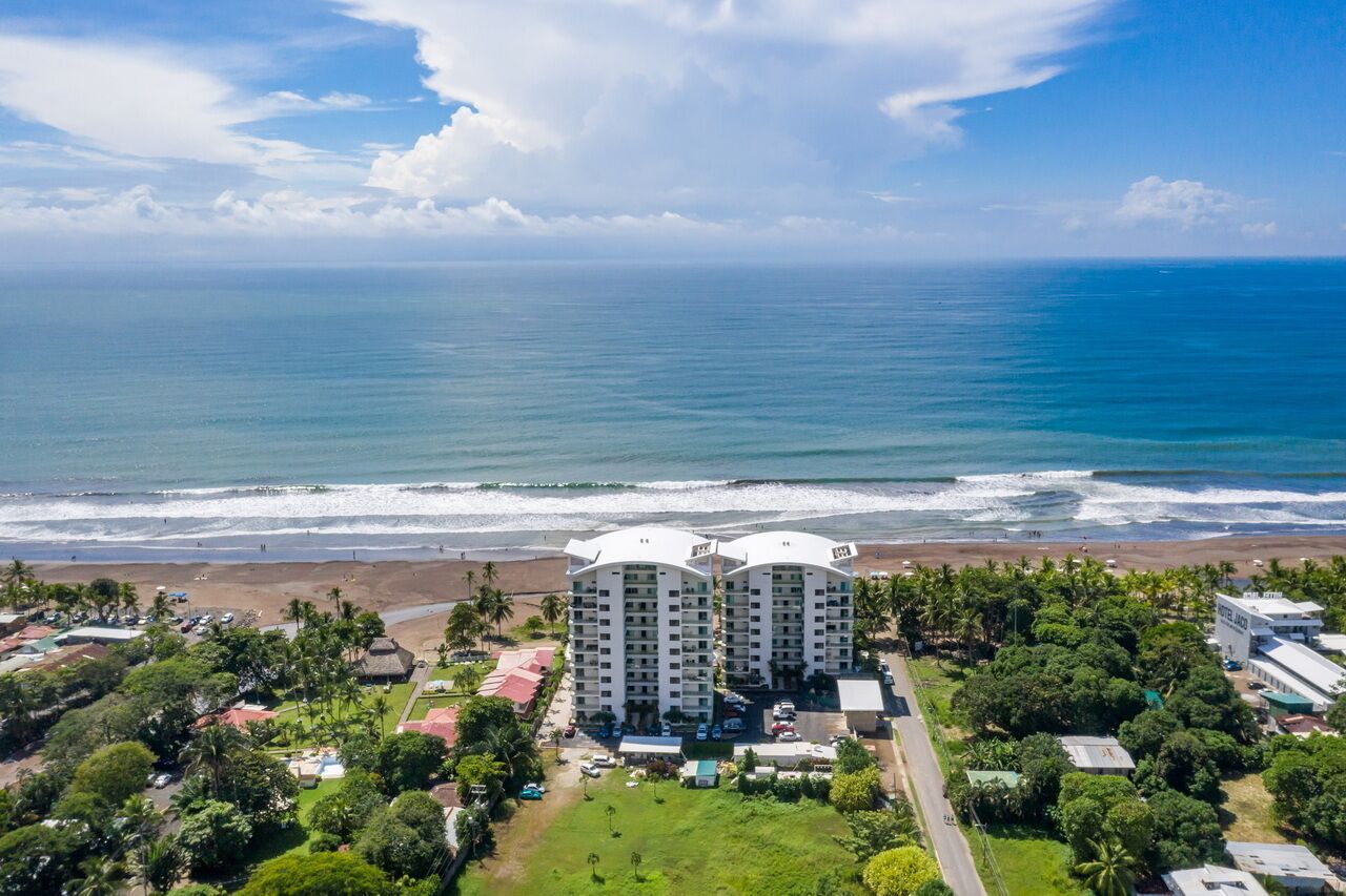 Een hotel met uitzicht op het strand, meerdere verdiepingen en een zwembad.