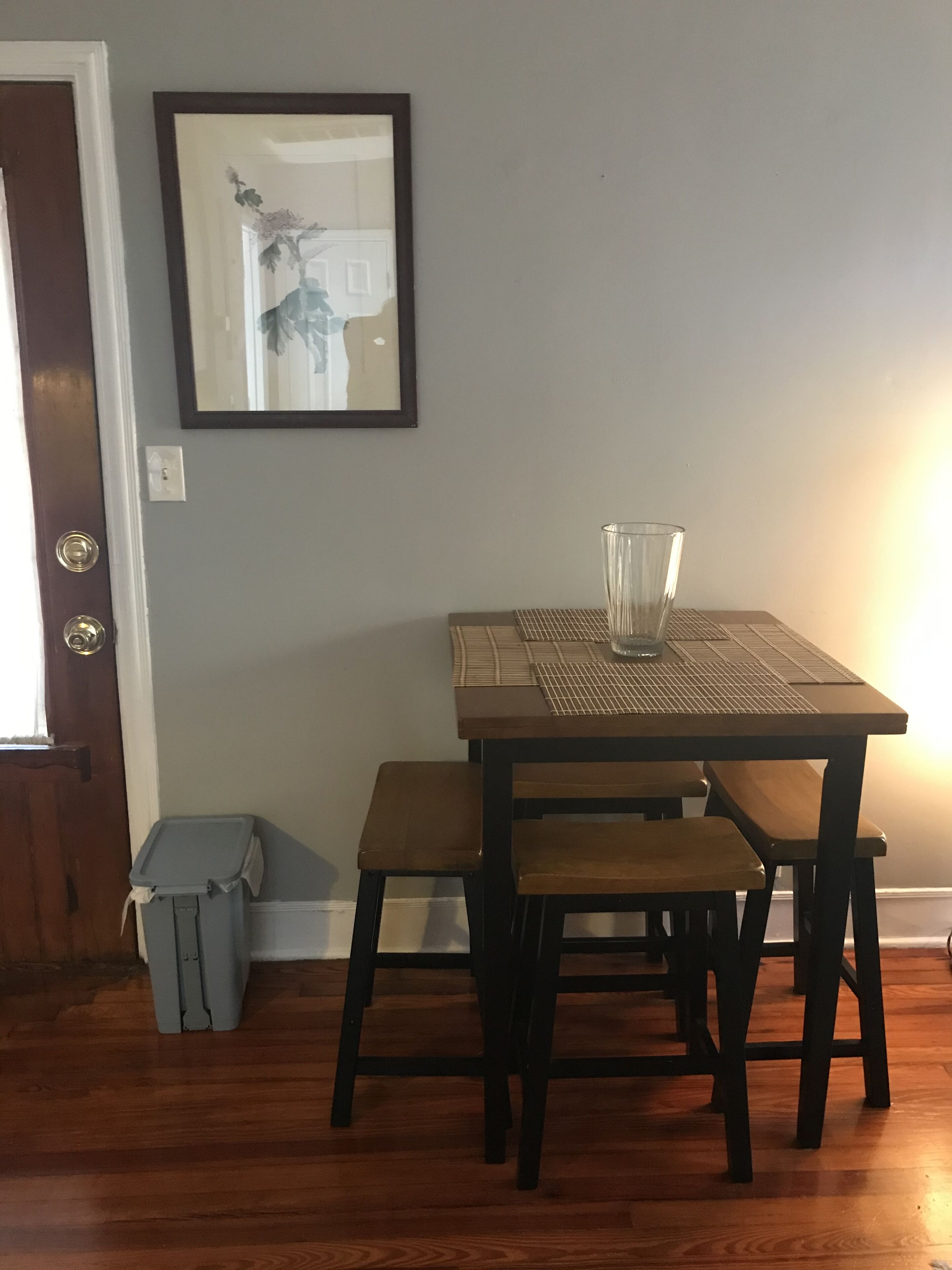 A dining table with a glass pitcher, two wooden benches, and a framed picture on the wall.