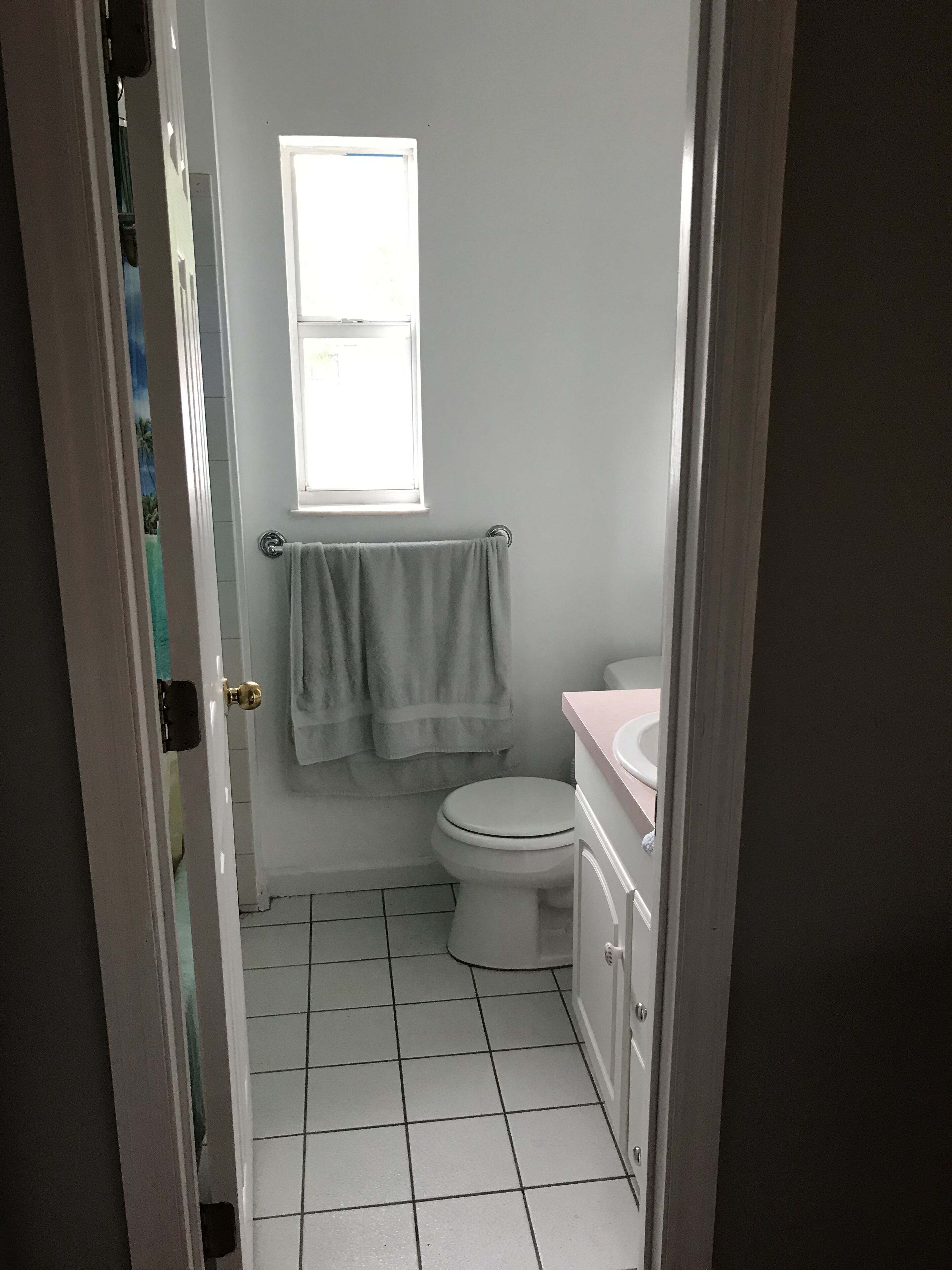 Ein kleines Badezimmer mit Toilette, Waschbecken und Fenster.