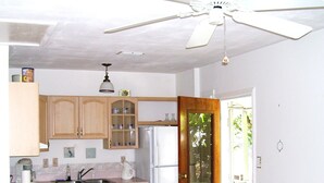 A kitchen with wooden cabinets, a refrigerator, a ceiling fan, and a door leading to a balcony.