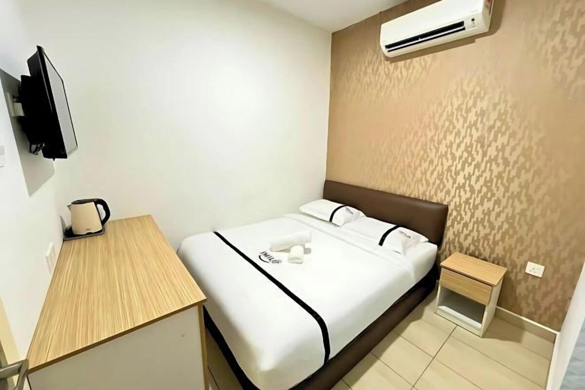 A hotel room with a bed, bedside table, and a TV mounted on the wall.