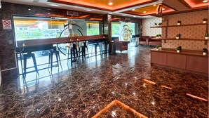 A modern bar area with a marble floor, seating, and a view of the street outside.