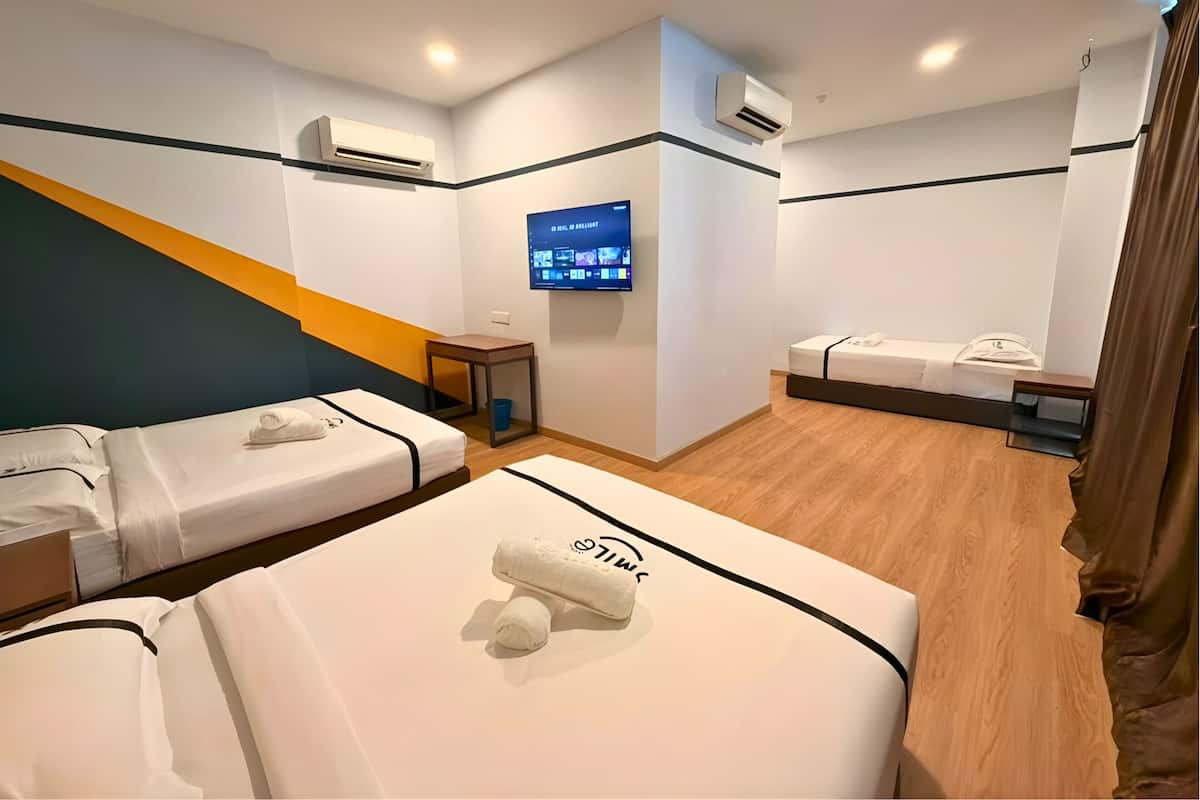 A hotel room with two beds, a TV, and air conditioning units.