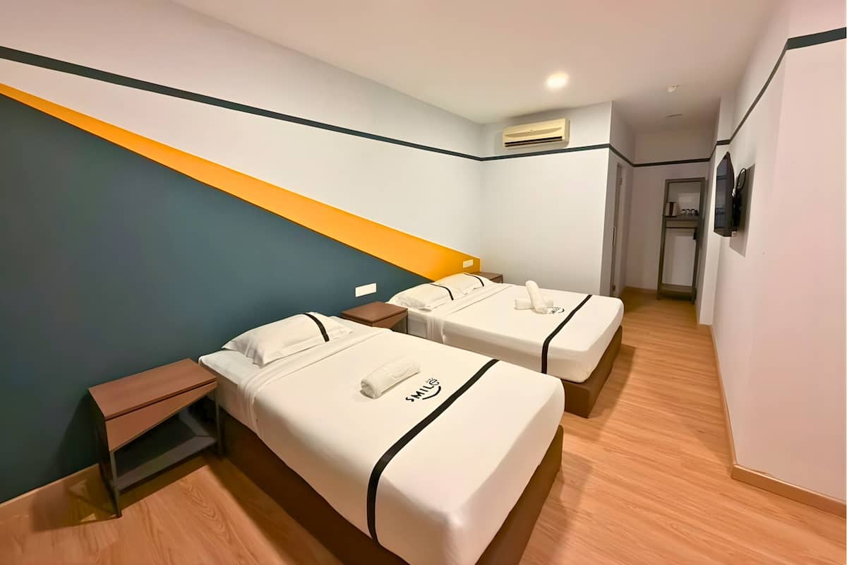 A hotel room with two beds, wooden flooring, a modern design, and a visible hallway.
