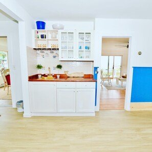 Una cocina moderna con armarios blancos, encimera de madera y una pared azul de acento.