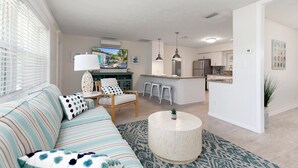 A modern living room with a striped sofa, a round coffee table, and a dining area with bar stools. - PROMO 5% WEEKLY AND 10% MONTHLY DISCOUNT
Private Beach Back Yard ! 5 BR 2 Bath  (Bradenton)