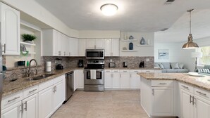A modern kitchen with white cabinets, granite countertops, stainless steel appliances, and a central island. - PROMO 5% WEEKLY AND 10% MONTHLY DISCOUNT
Private Beach Back Yard ! 5 BR 2 Bath  (Bradenton)