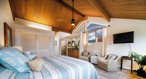 Une chambre à coucher avec un lit, une télévision, des meubles en osier et un ventilateur de plafond.
