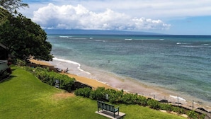 Ein Strand mit einer Bank, einer Rasenfläche und Blick auf das Meer.