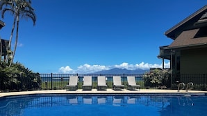 Ein klares, blaues Schwimmbecken mit Liegestühlen und Blick auf den Ozean und die Berge.