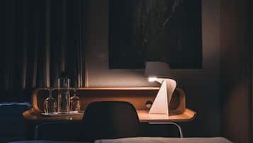 Una habitación de hotel con cama, mesita de noche con lámpara y un cuadro colgado en la pared.