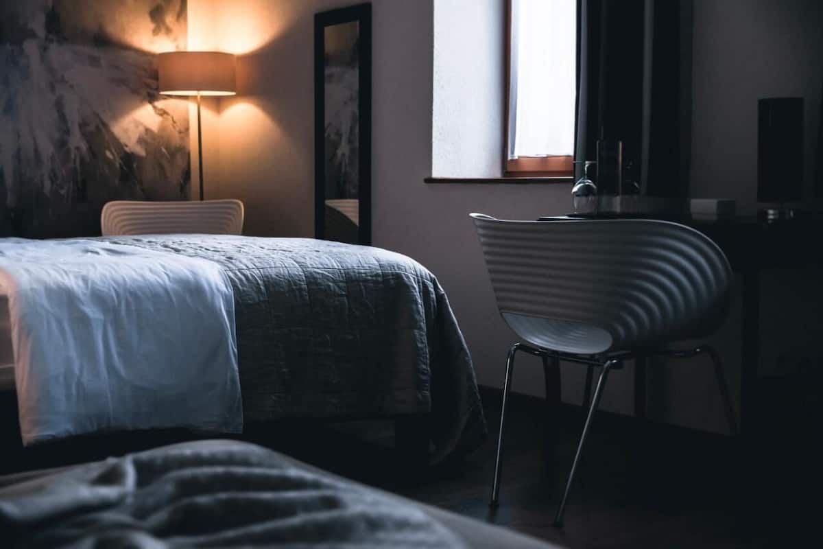 A bedroom with a bed, a chair, a desk, and a lamp.