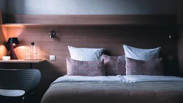 A hotel room with a bed, a bedside table with a lamp, and a chair.