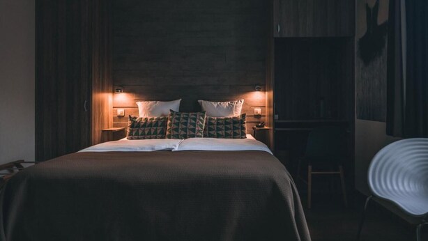 Un dormitorio con una cama grande, dos mesitas de noche con lámparas, una silla y un armario.