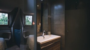Un baño moderno con un lavamanos grande, muebles de madera oscura y vistas al exterior a través de una ventana.