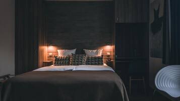 A bedroom with a large bed, two bedside tables with lamps, a chair, and a wardrobe.