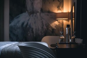 A hotel room with a bed, a bedside table with two wine glasses and a bottle, and a large abstract painting on the wall. - Logis Hôtel Frankenbourg (Rocamadour)