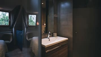 Un baño moderno con un lavamanos grande, muebles de madera oscura y vistas al exterior a través de una ventana.