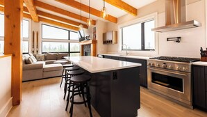 Eine moderne Küche mit einer großen Kochinsel, integriertem Backofen und einem Essbereich mit einer Couch und Barhocker.
