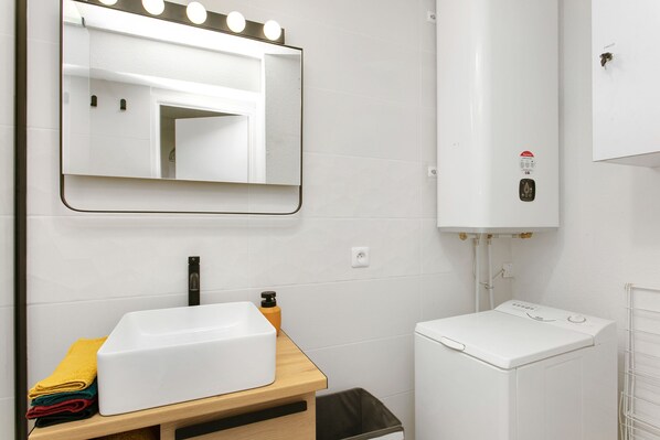 A bathroom with a sink, mirror, and a washing machine. - F3 Terrace with ocean view, swimming pool, parking, and air conditioning (Sète)