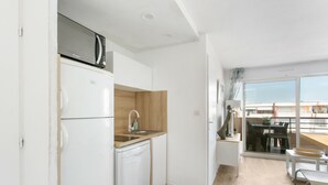 A modern kitchen with white appliances, a wooden countertop, and a view of the balcony. - F3 terrace sea view, swimming pool, parking and air conditioning (Sète)