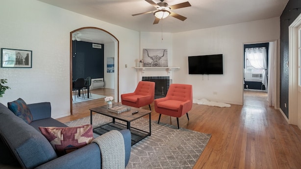 A living room with a sofa, two armchairs, a coffee table, a fireplace, and a ceiling fan. - F1 •  30% OFF • Updated, Cozy & Clean • Fast WiFi • 2BR/2BA Monthly Rental (San Antonio)