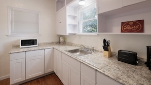 A kitchen with white cabinets, a granite countertop, a microwave, a toaster, and a window with blinds. - F1 •  30% OFF • Updated, Cozy & Clean • Fast WiFi • 2BR/2BA Monthly Rental (San Antonio)