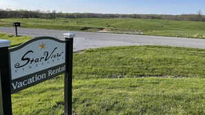Señal de StarView Vineyard Vacation Rental, con vista a un campo verde y una carretera.