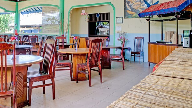 A restaurant with wooden tables and chairs, a cash register, and a blue awning. - Capital O 90417 Hotel Batu Suli Internasional (Palangkaraya)