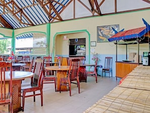 Un restaurant avec des tables et des chaises en bois, une caisse enregistreuse et un auvent bleu.