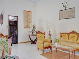 Una habitación con sofá, sillón y una mesa con un jarrón de flores.