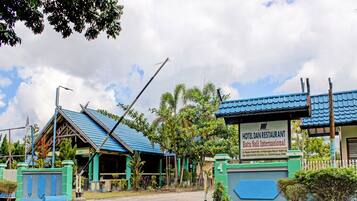 A hotel with a blue roof, a signboard, and a gated entrance.