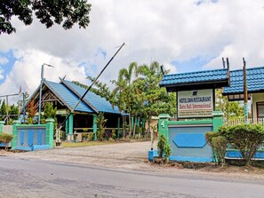 A hotel with a blue roof, a signboard, and a gated entrance. - Capital O 90417 Hotel Batu Suli Internasional (Palangkaraya)